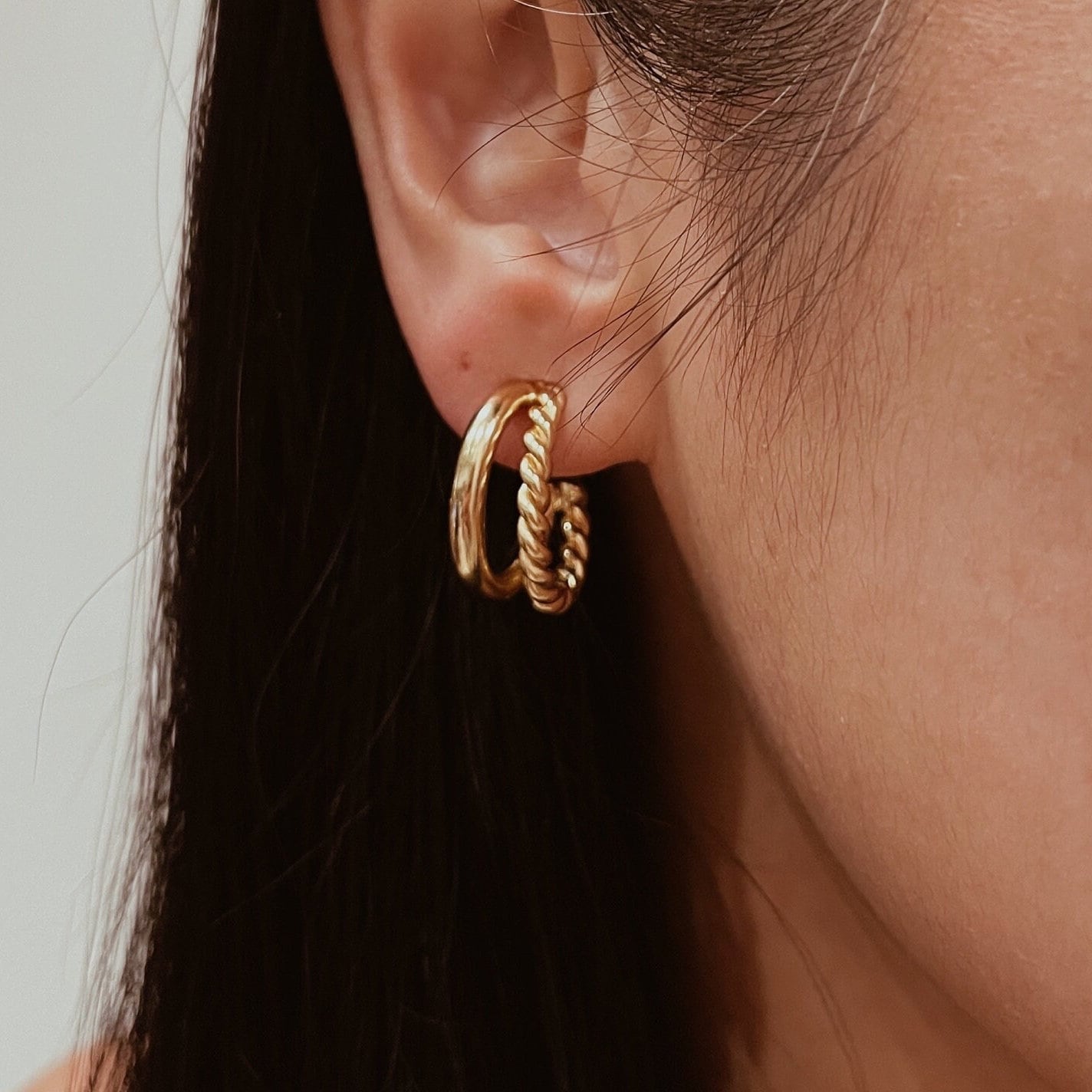 Gold twisted double hoop earrings with a braided design