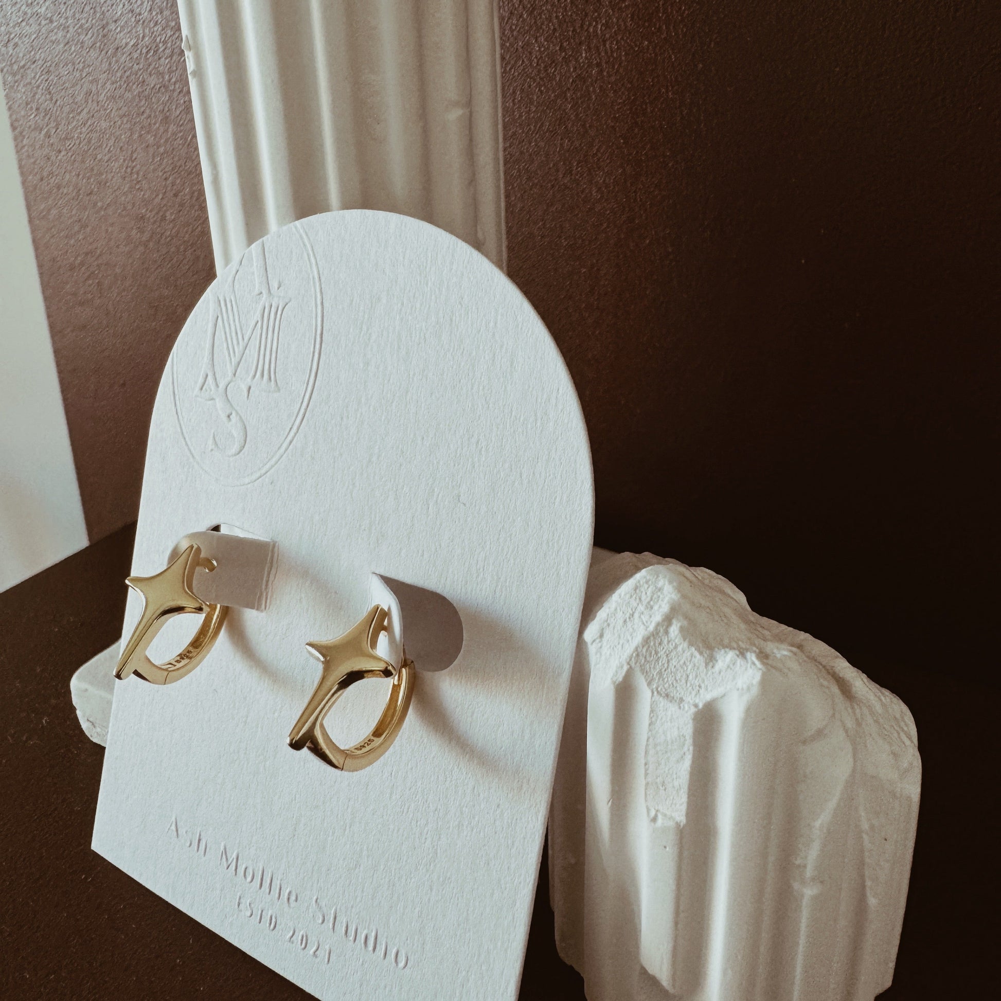 Gold hoop earrings with starburst design and polished finish